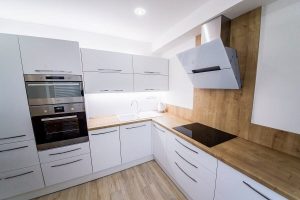 Biela moderná kuchyňa s drevom do L