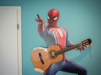 Spiderman na stene drží gitaru